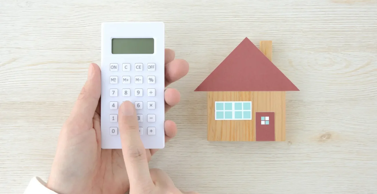 Mains utilisant une calculatrice financière pour analyser des documents de simulation de crédit immobilier