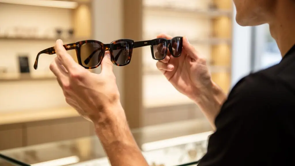 Un opticien compare côte à côte deux montures en acétate au-dessus d'un comptoir.